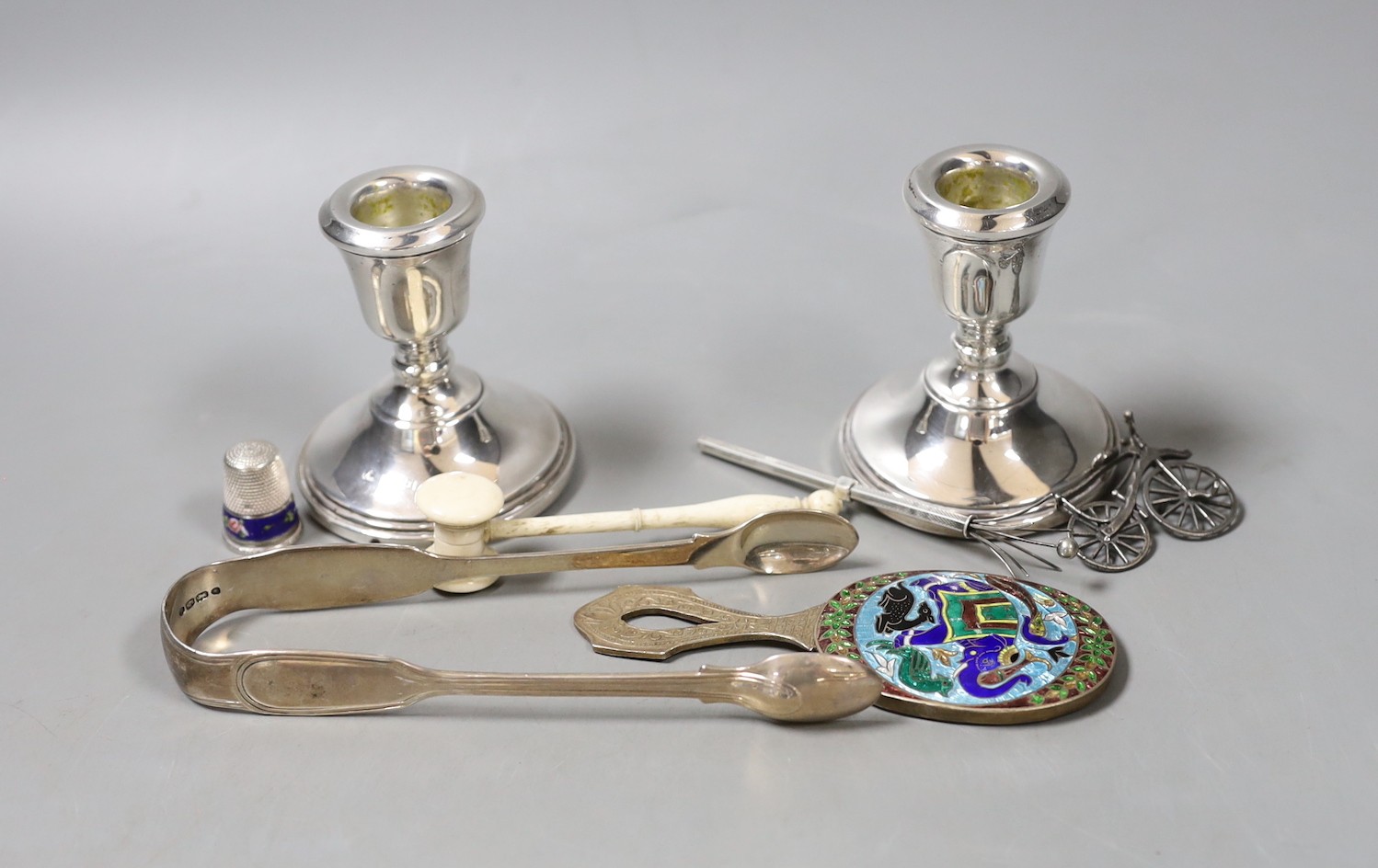 A group of mixed silver, to include sugar tongs, a pair of candlesticks, an Indian silver enamel mirror, a miniature bone gavel and other items